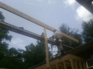 Carpenter setting a ridge beam over a new addition frame — Ice Dam Removal by Roofing Brothers in Helena