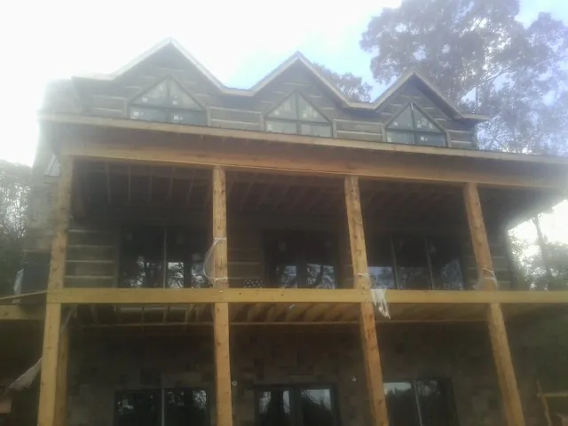 Dormers and porch framing on a large log home under construction — Roof Coating work by our crew in Helena