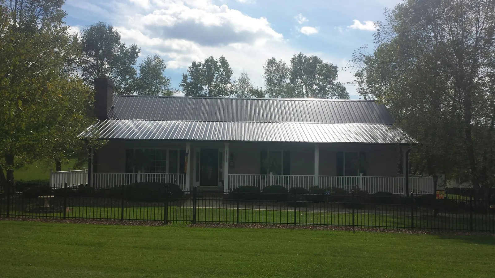 Gray metal roof on a brick ranch with a full width front porch — Gutter Guard Installation work by our crew in Helena