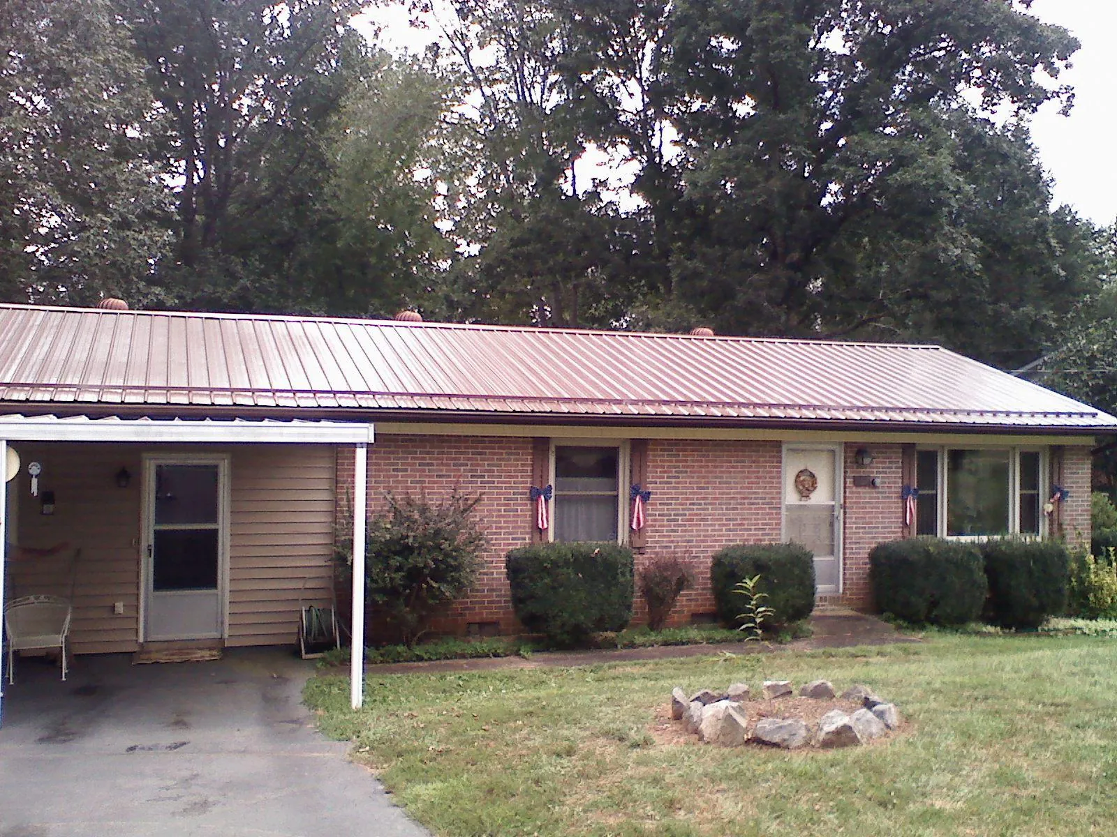Bronze metal roof and carport on a brick ranch home — Roof Repair work by our crew in Helena