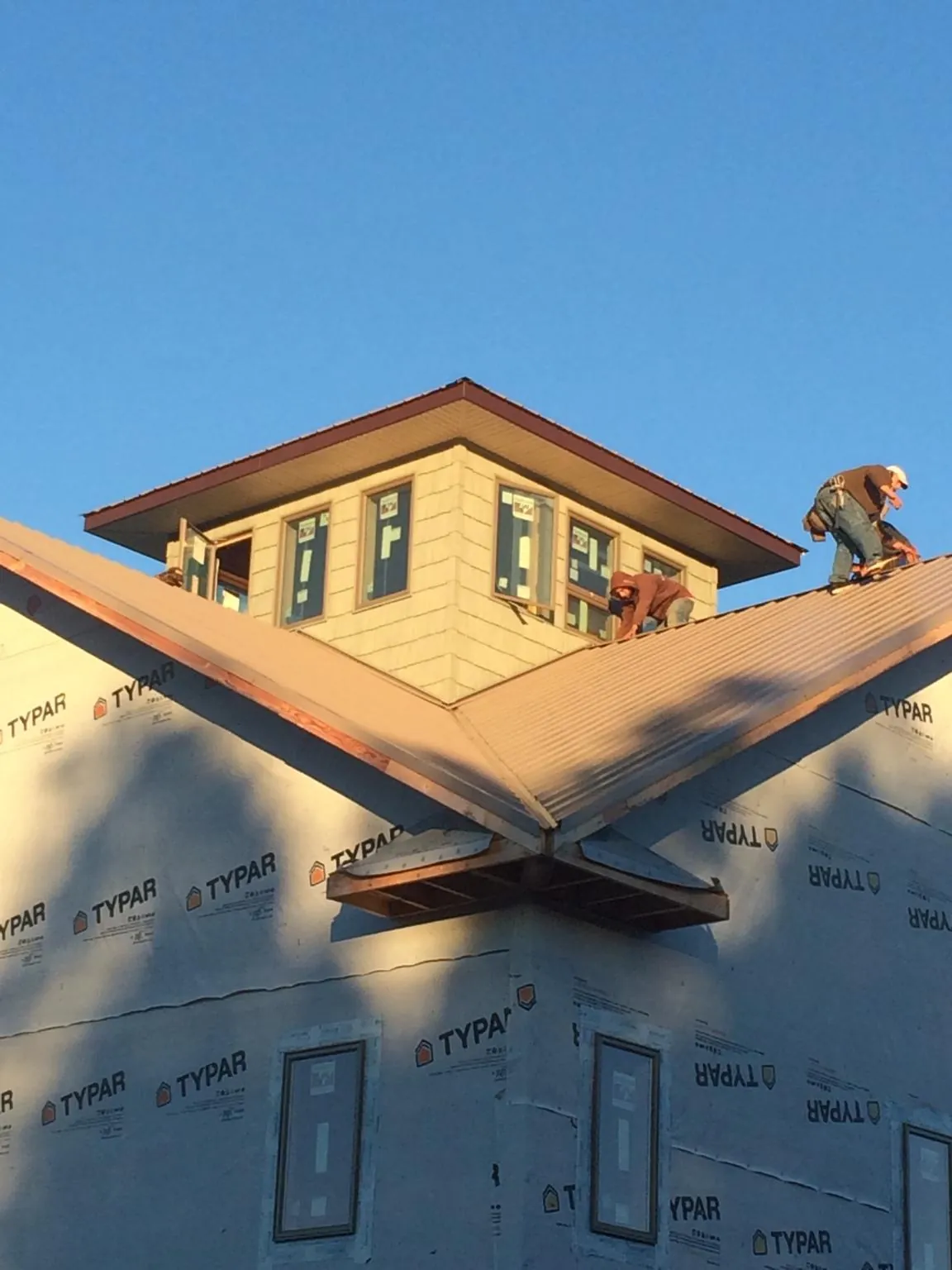 Roofers working around a rooftop cupola on a new metal roof at sunset — Roof Waterproofing in Helena by Roofing Brothers